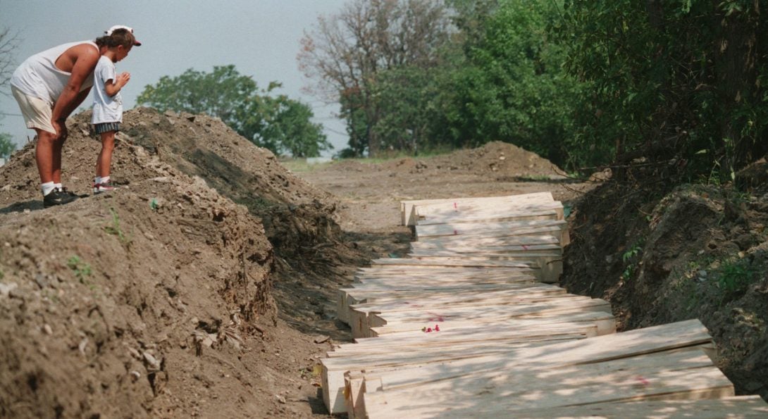 A father and son pray at a mass gravesite after tossing a flower onto the coffins at the Homewood Memorial Cemetery in Homewood IL. More than 40 of the forgotten and unclaimed victims of Chicago’s 1995 July summer heat disaster are buried at the cemetery.